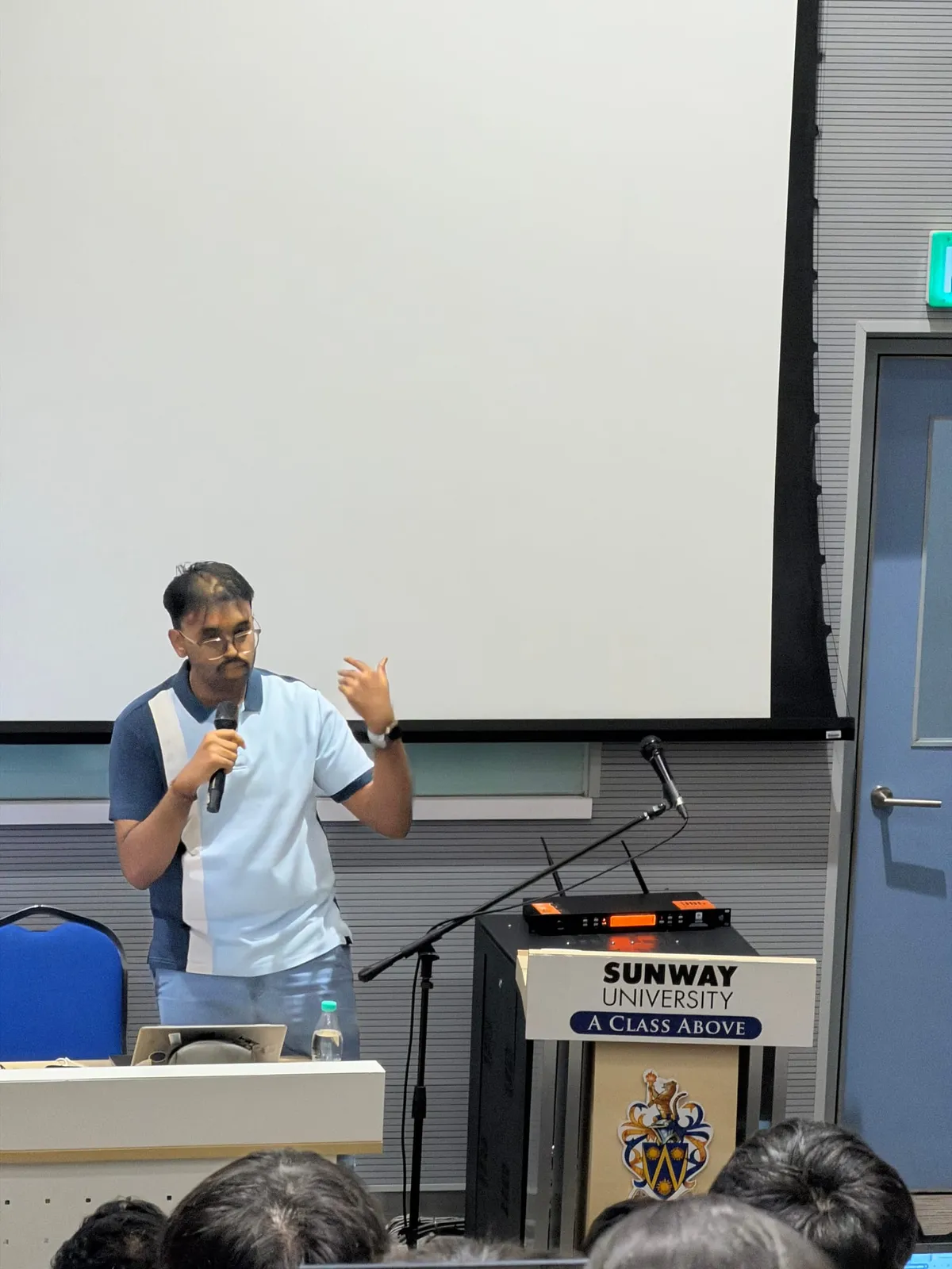 Puvaan Raaj holding a microphone and gesturing while presenting at Sunway University